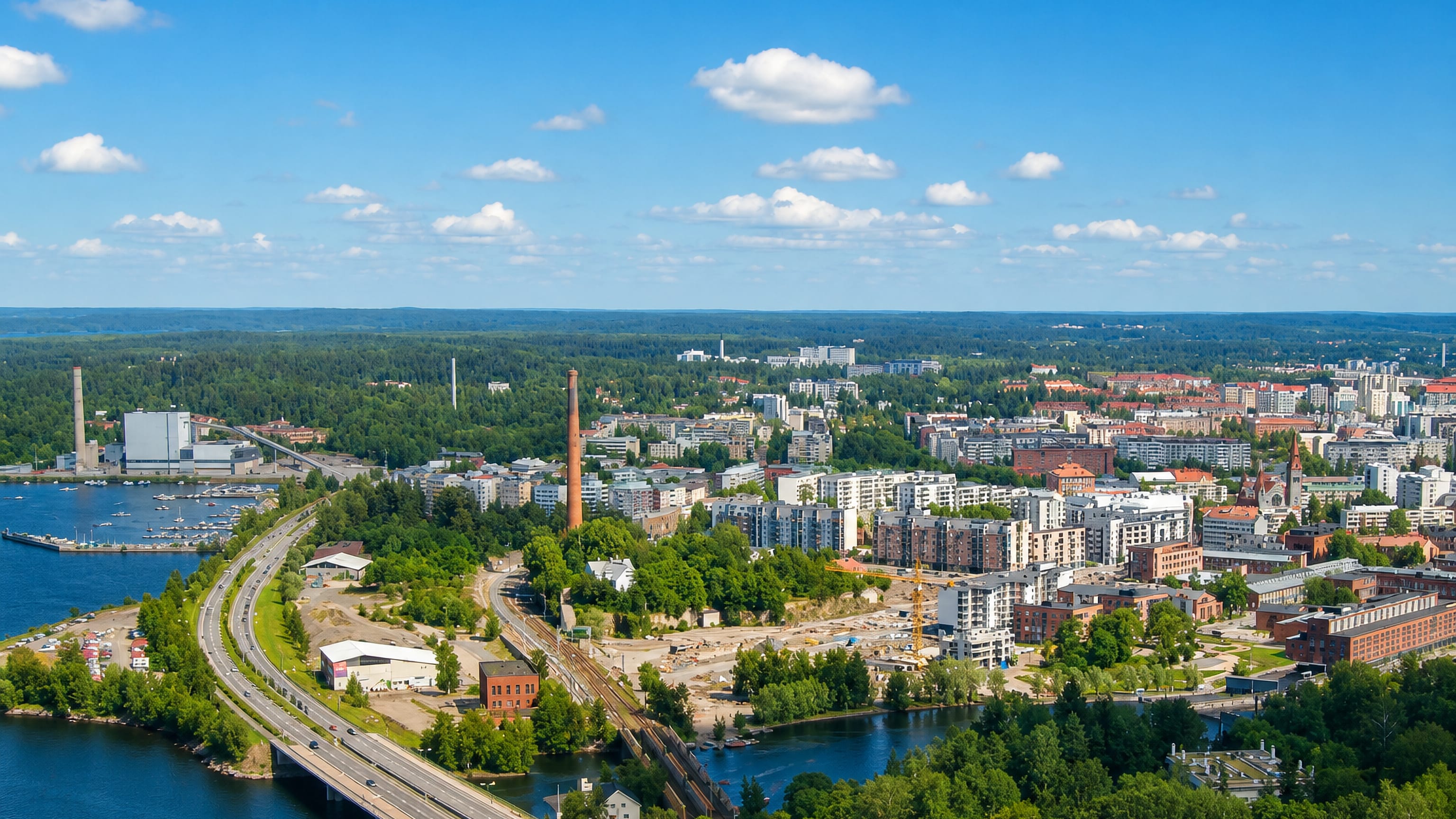 Aerial daytime view of Tampella, Tampere, with its red-brick factory chimney, lakeside waterfront and modern apartment blocks.