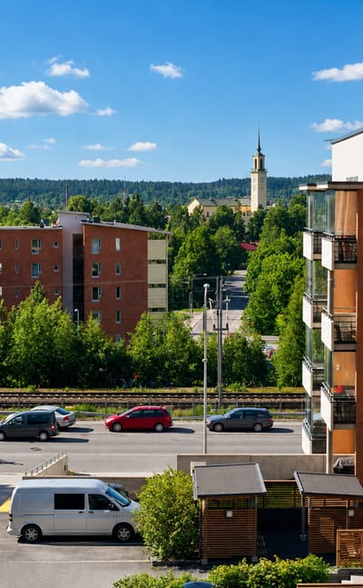 Red-brick apartment blocks, a distant church spire and wooded ridges seen across Viinikka in Tampere.