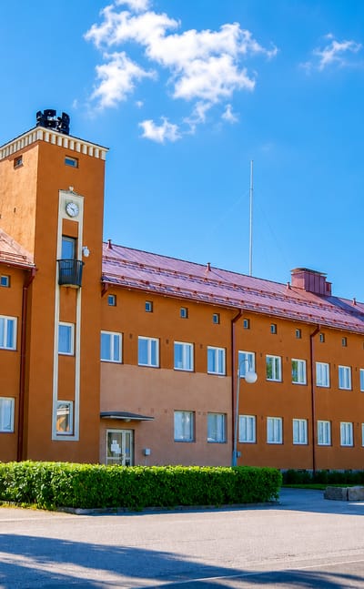 Pedersore's ochre functionalist municipal hall with clock tower and flags under a blue sky