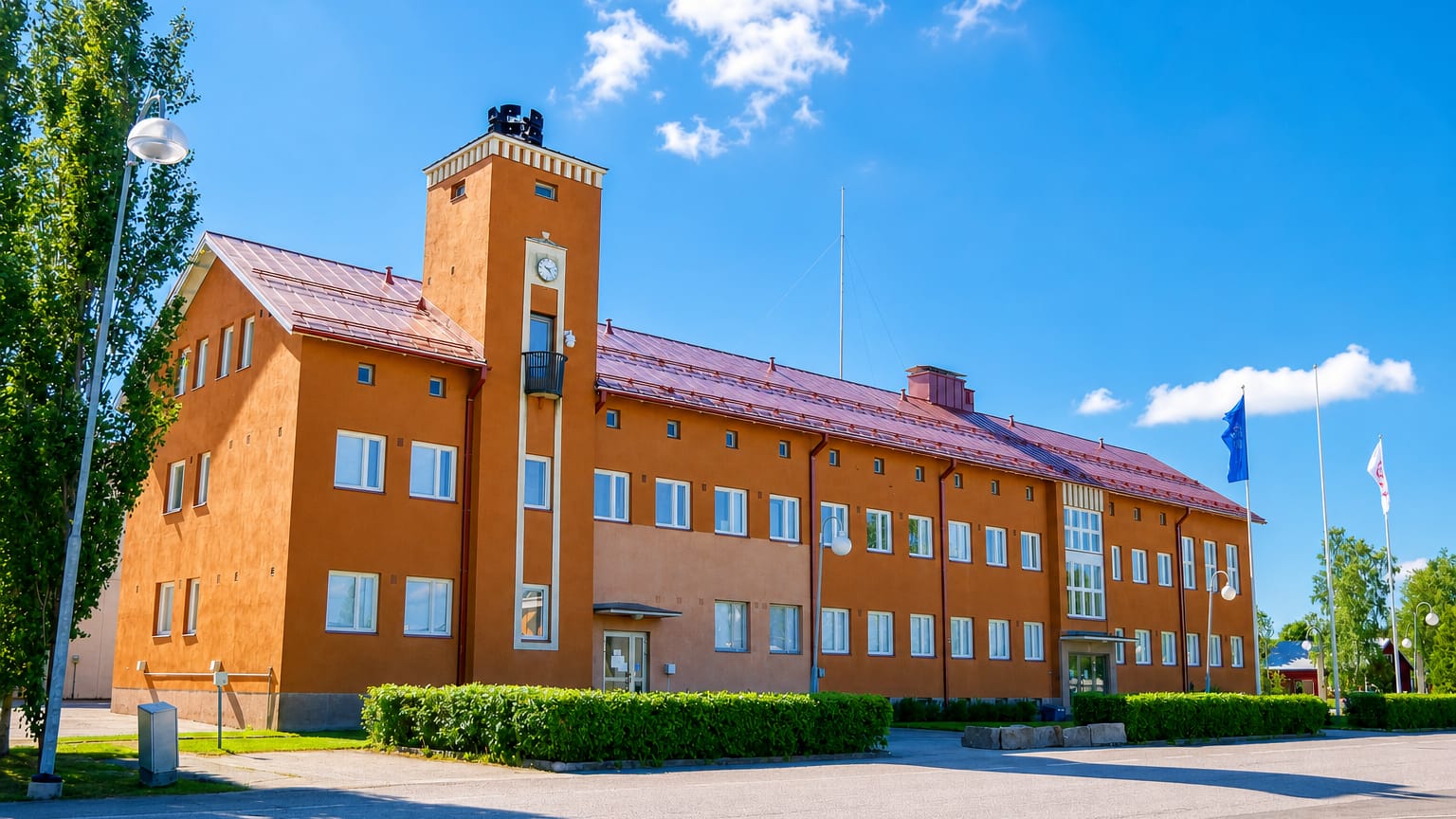 Pedersore's ochre functionalist municipal hall with clock tower and flags under a blue sky