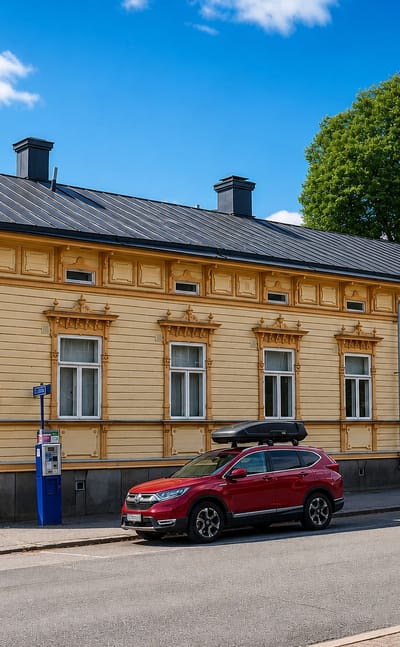 Ornate yellow wooden house with a seam-metal roof along a sunny street in III kaupunginosa, Vaasa.