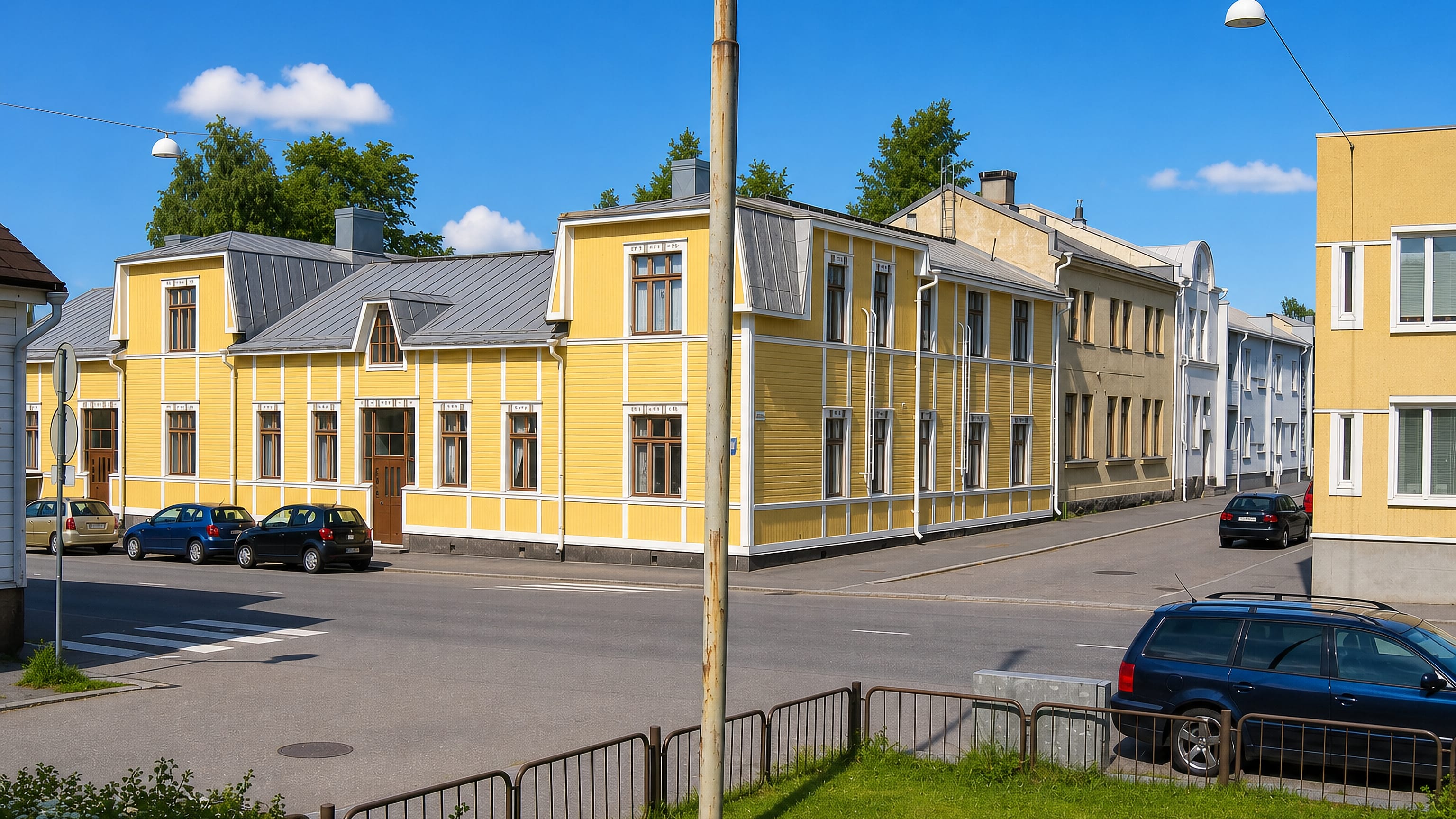 Yellow wooden houses with white trim along a quiet sunlit street in VIII kaupunginosa, Vaasa.