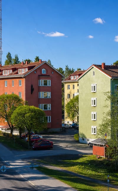 Colorful functionalist apartment blocks along a quiet birch-lined residential street in Niinivaara, Joensuu, Finland