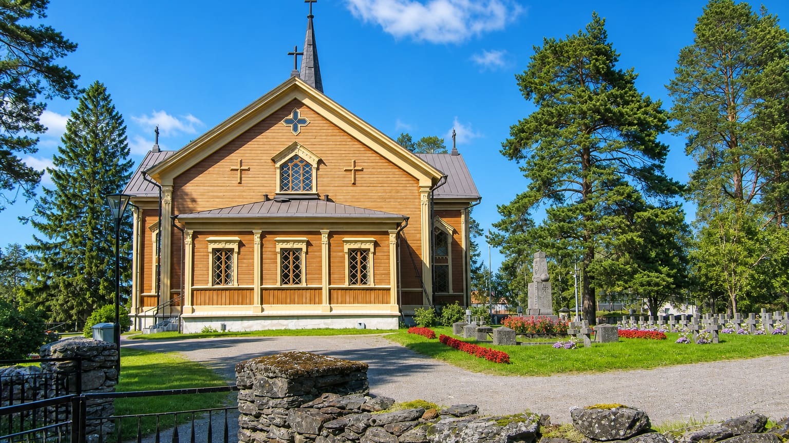 Yellow wooden church with a dark spire beside its cemetery in Kontiolahti, Finland.