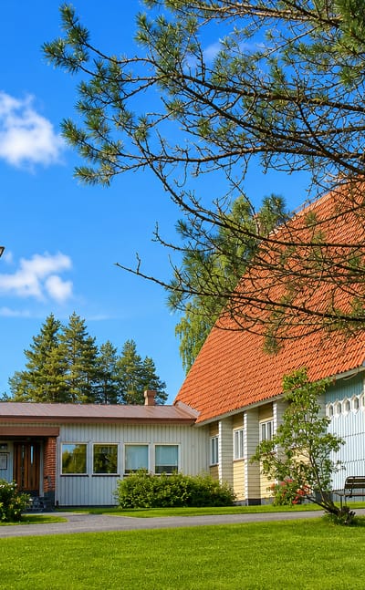 Liperi's modern church with a tall freestanding bell tower and orange-tiled roof on a summer day.