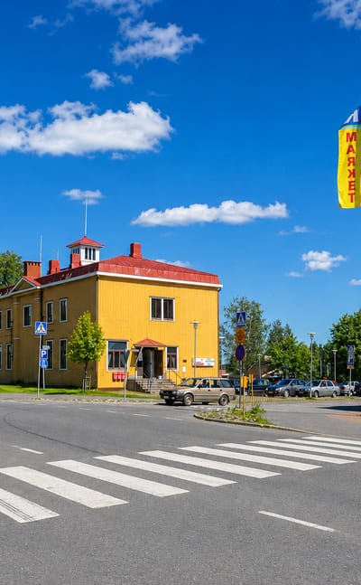 A yellow wooden building beside a K-Market and street crossing in Tohmajärvi, eastern Finland.