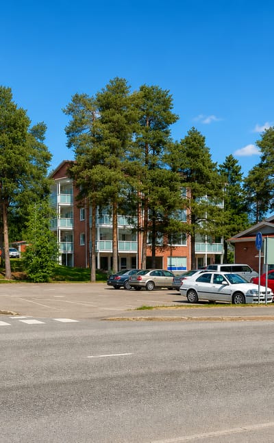 A tree-lined street in Haapavesi, Finland, with an apartment block and low buildings beside a quiet road.