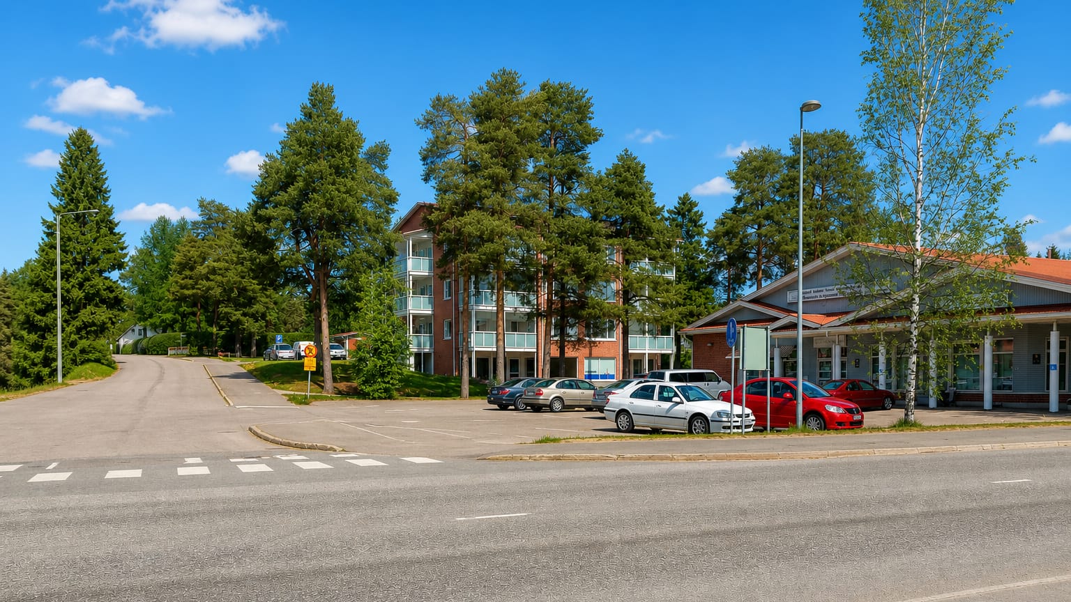 A tree-lined street in Haapavesi, Finland, with an apartment block and low buildings beside a quiet road.