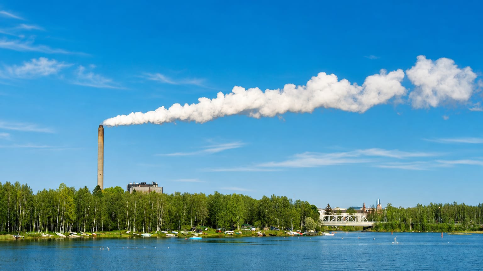 Tall power-plant chimney trailing a steam plume across the bay from the forested shores of Hietasaari, Oulu.