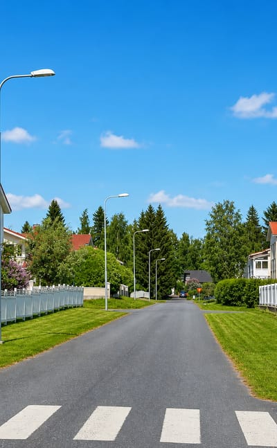 Quiet street of red-roofed white timber houses in Hintta, Oulu, on a clear summer day.