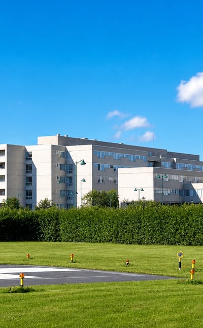 Hospital buildings and a helipad set behind trees and lawn in Kontinkangas, Oulu's healthcare district.