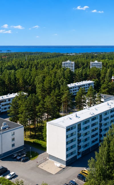 White apartment blocks among pine forest with the sea beyond at Lintula in Oulu.