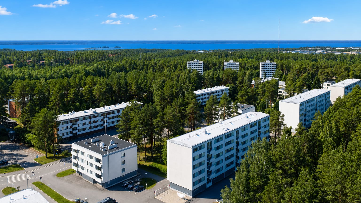 White apartment blocks among pine forest with the sea beyond at Lintula in Oulu.