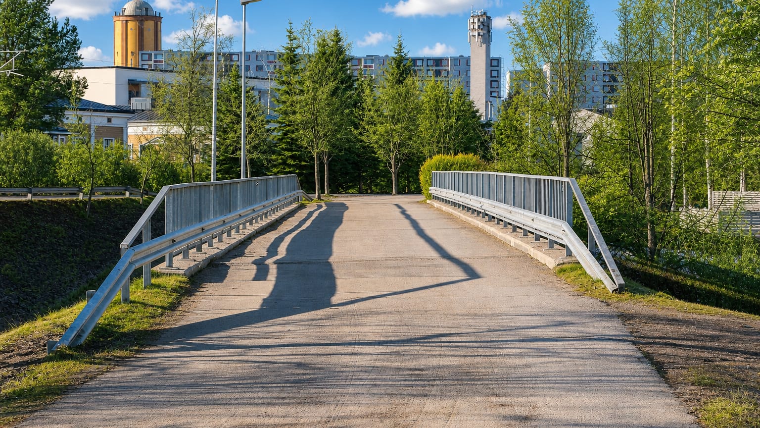 Pedestrian footbridge leading toward apartment blocks and towers in Myllytulli, Oulu, on a sunny summer day