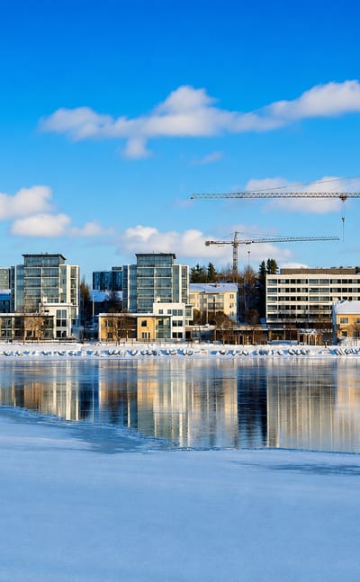 Tuira's riverside apartment blocks above the frozen Oulujoki under a blue winter sky in Oulu, Finland