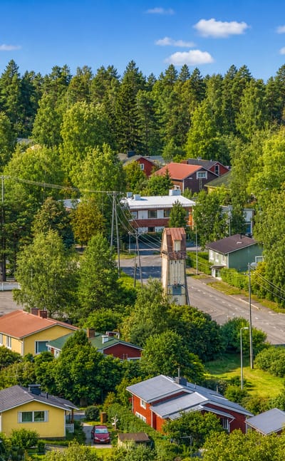 Wooden houses and pine forest above a quiet road in the Valivainio district of Oulu, Finland