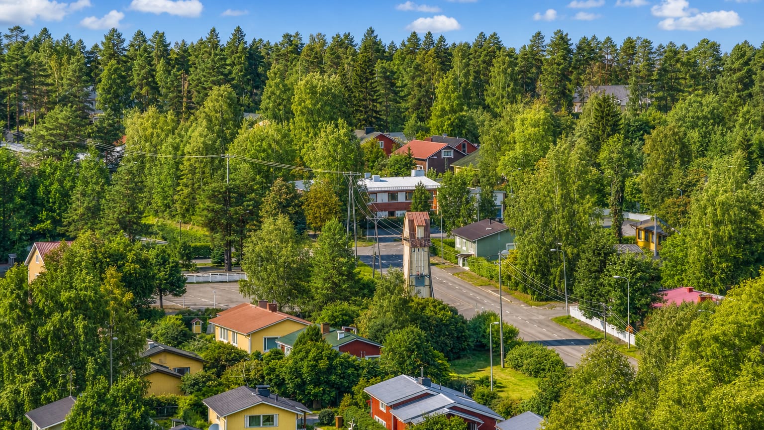 Wooden houses and pine forest above a quiet road in the Valivainio district of Oulu, Finland