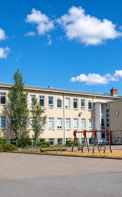 School building with a playground and flagpole in the village of Piippola, Finland