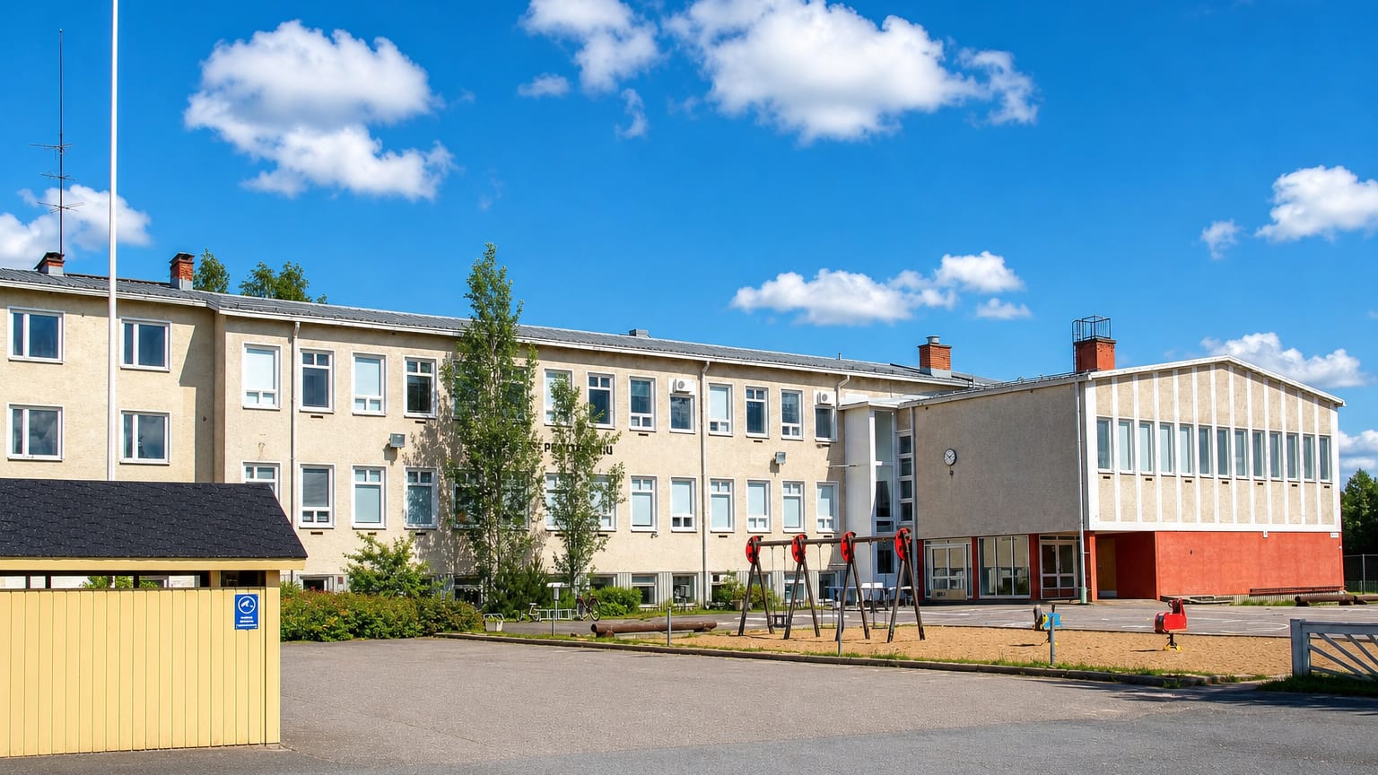 School building with a playground and flagpole in the village of Piippola, Finland