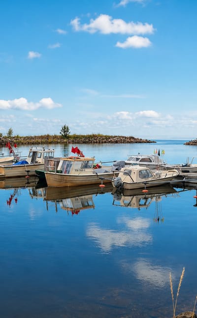 Small boat harbor with moored boats, a rocky breakwater and a beacon on the calm Gulf of Bothnia coast at Siikajoki, Finland