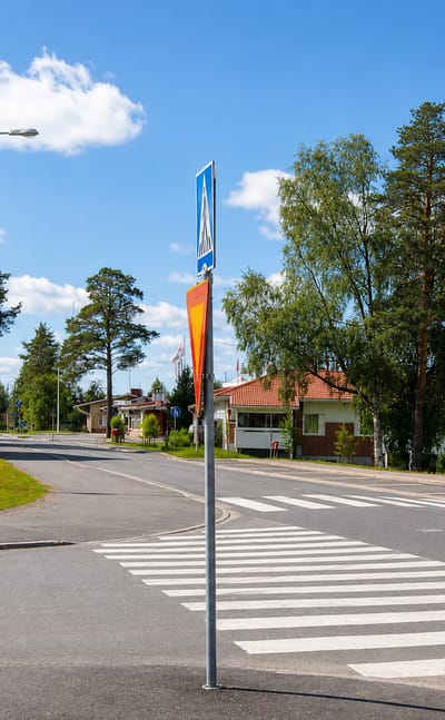 Village crossroads with a red timber house and a pedestrian crossing in Ylikiiminki, Finland