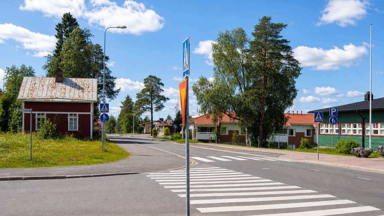 Village crossroads with a red timber house and a pedestrian crossing in Ylikiiminki, Finland