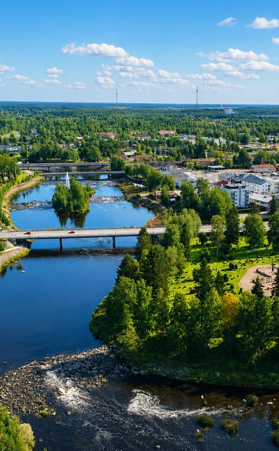 Aerial view of Ylivieska, Finland, the Kalajoki river winding under bridges past apartment blocks and a red-brick tower