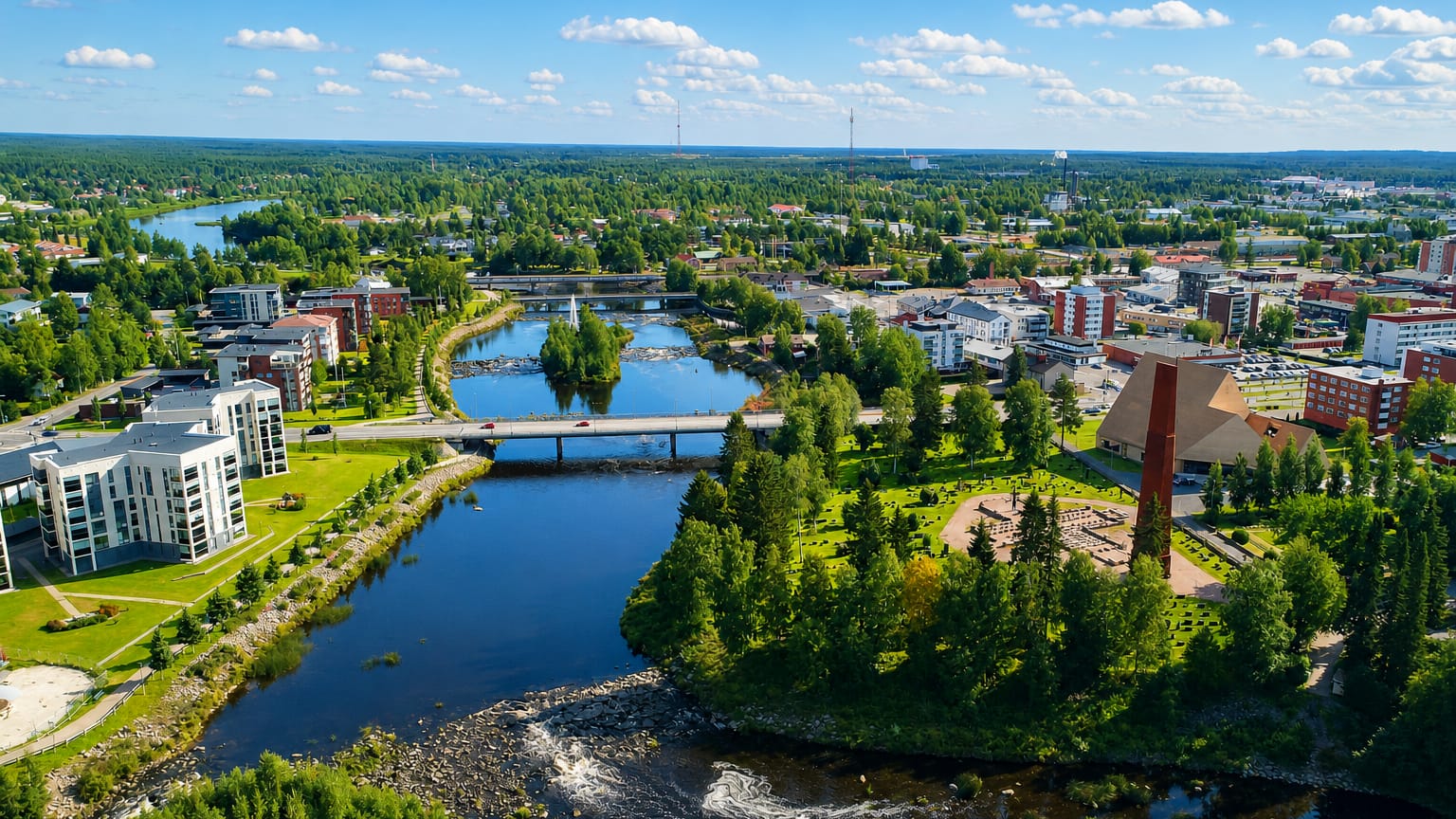 Aerial view of Ylivieska, Finland, the Kalajoki river winding under bridges past apartment blocks and a red-brick tower