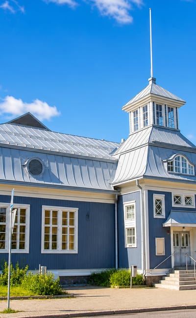 A historic blue wooden building with a white cupola tower in central Iisalmi, Finland.