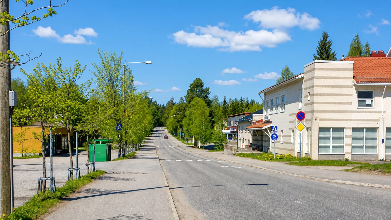 Quiet tree-lined main street through Rautavaara, Finland with a modern building and road signs.