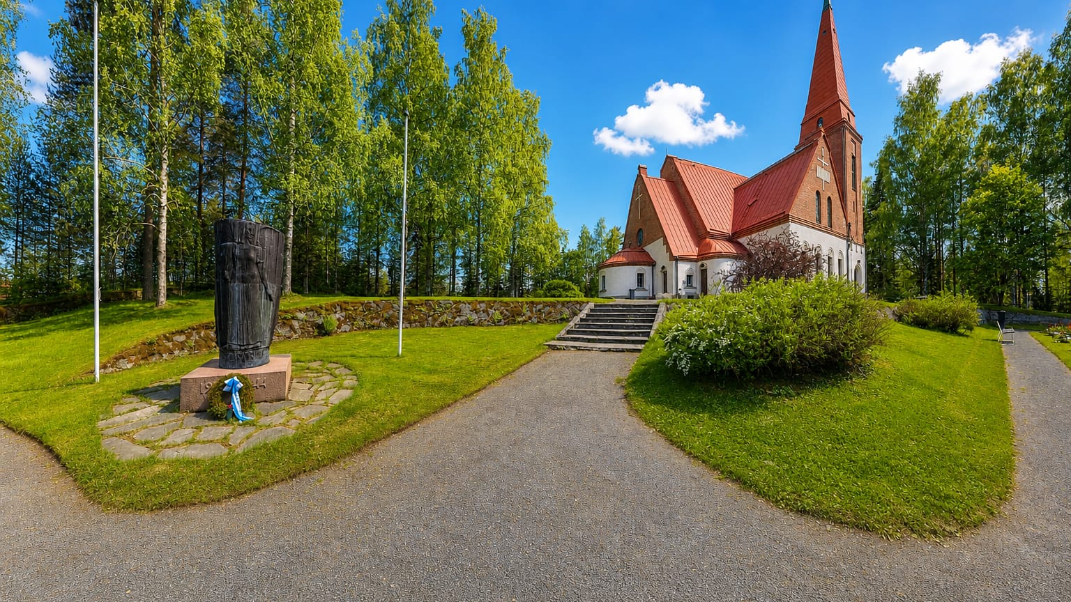 Siilinjärvi's red-brick church with a tall spire and tiled roof beside a war memorial in a green churchyard.