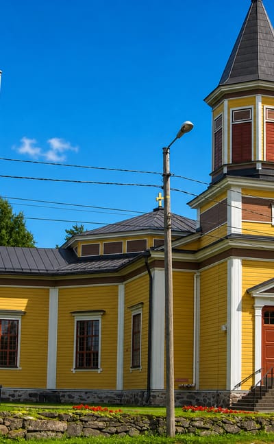 Yellow wooden church with an octagonal tower and stone wall at Vesanto, Finland