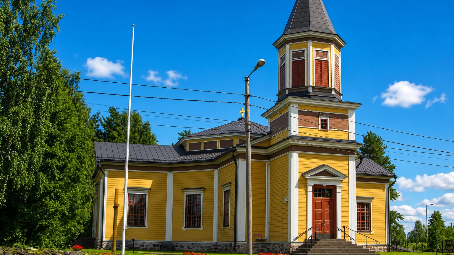 Yellow wooden church with an octagonal tower and stone wall at Vesanto, Finland