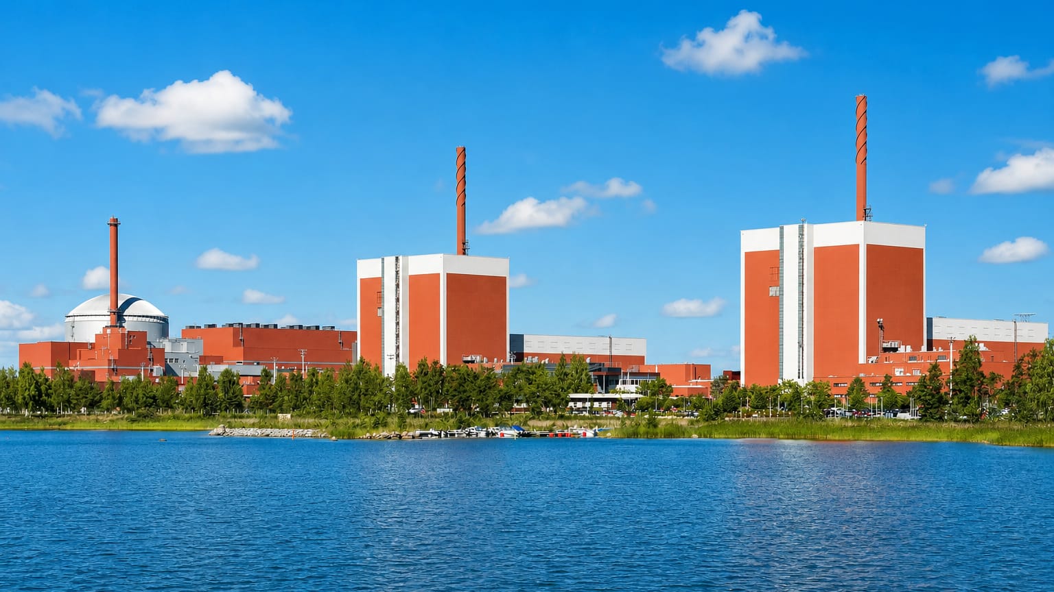 Olkiluoto Nuclear Power Plant at Eurajoki, Finland, its red reactor buildings and striped stacks beside calm blue coastal water