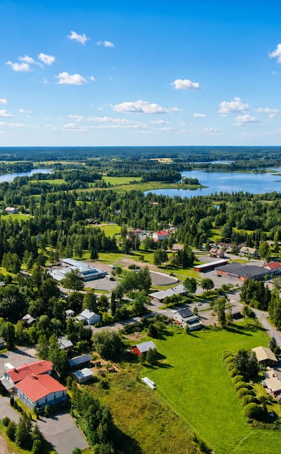 Aerial view of Jämijärvi, a small Finnish town set among pine forests beside its namesake lake under a blue summer sky.