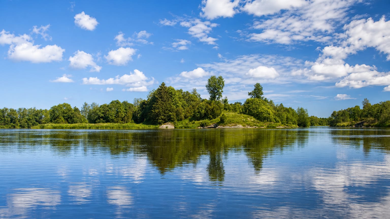 Calm river in Kokemäki, Finland, with a wooded islet and forested shore mirrored in still water under a blue summer sky.