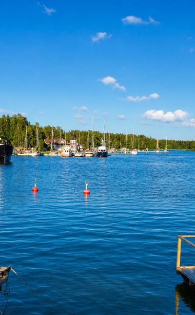 Merikarvia guest harbour on the Gulf of Bothnia, with moored sailboats, red mooring buoys and a wooden jetty under a blue sky.