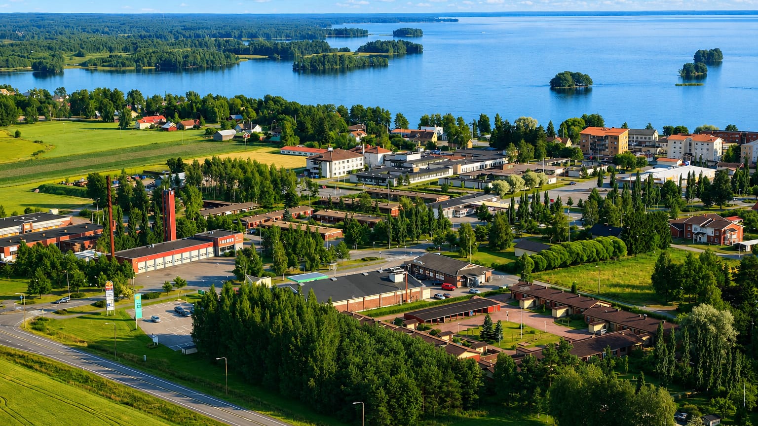 Aerial view of Säkylä, Finland, a low-rise lakeside town on the shore of Pyhäjärvi amid fields and forest.