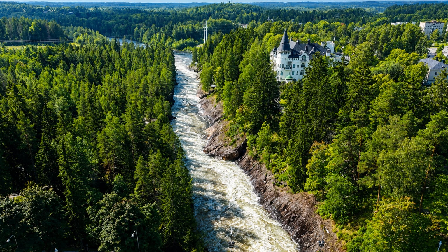 Aerial view of the Imatrankoski rapids on the Vuoksi River with the castle-like State Hotel amid pine forest, Imatra, Finland