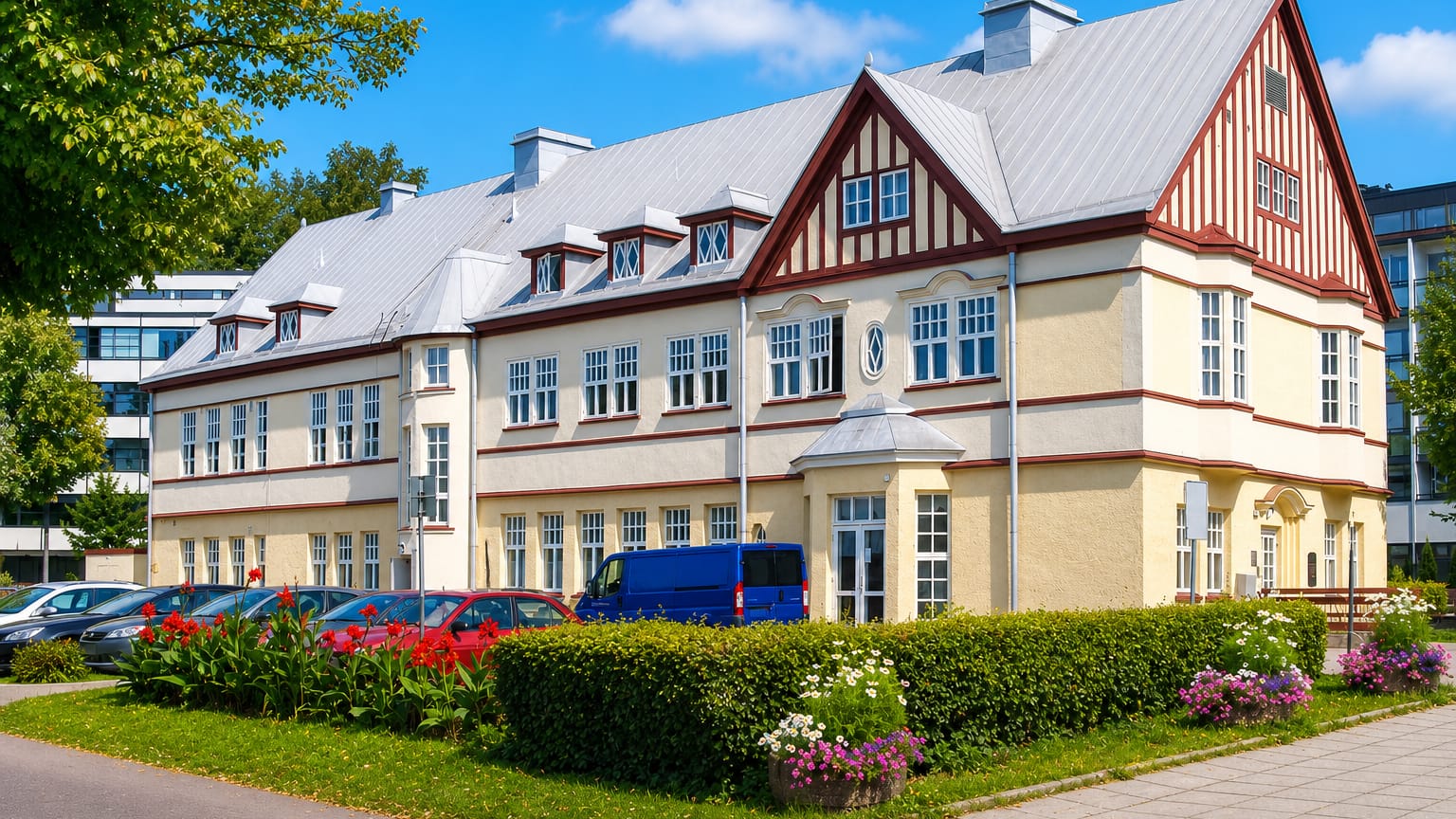 Cream and red half-timbered spa-era building in Kylpylä, Lappeenranta, with flower beds and clipped hedges.