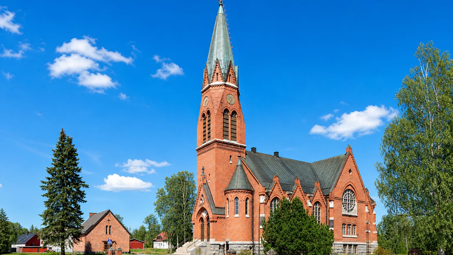 Red-brick neo-Gothic church with a tall green spire under blue sky in Kauhava, Finland
