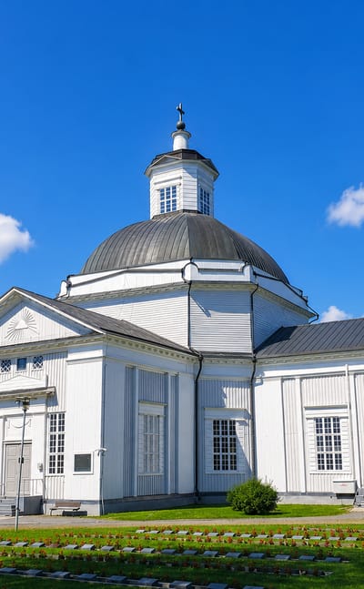 White neoclassical domed church above a foreground cemetery under a clear sky in Lapua, Finland.