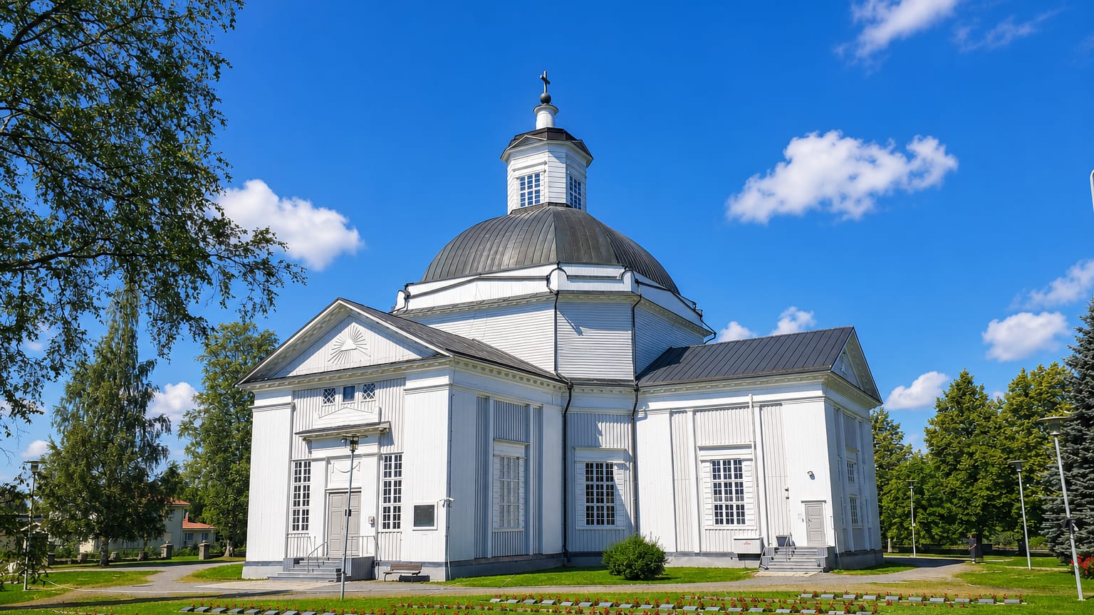 White neoclassical domed church above a foreground cemetery under a clear sky in Lapua, Finland.