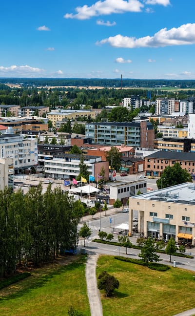 Elevated daytime view over central Seinäjoki, Finland, with mid-rise buildings and flat forested plains reaching the horizon.