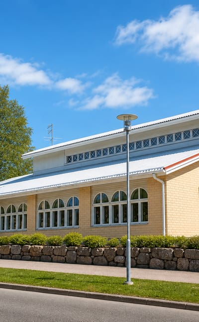 Modern yellow-brick community hall with arched windows and a crested facade in Enonkoski, Finland.