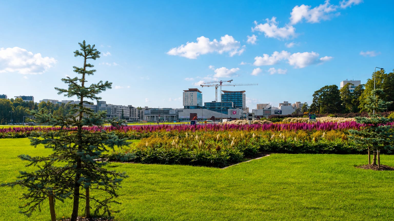Tapiola's modernist skyline of towers rising beyond a green park with colourful flowerbeds and a young spruce, Espoo, Finland