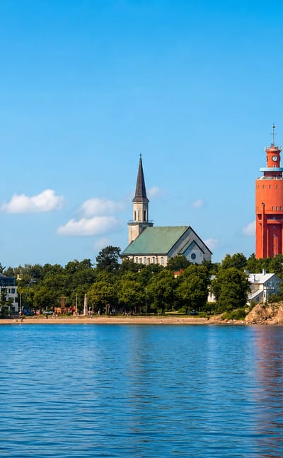Hanko seafront skyline with its red brick water tower, green-spired church and white wooden villas under a blue sky.