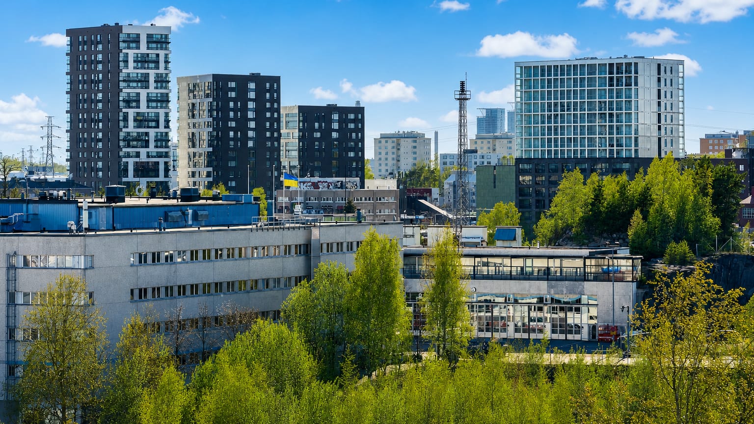 Herttoniemi's modern apartment towers and low industrial blocks rising above birch-covered green slopes in eastern Helsinki