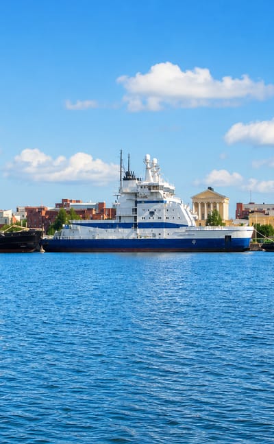 Icebreaker fleet moored along the Katajanokka quay in Helsinki with neoclassical waterfront buildings behind.