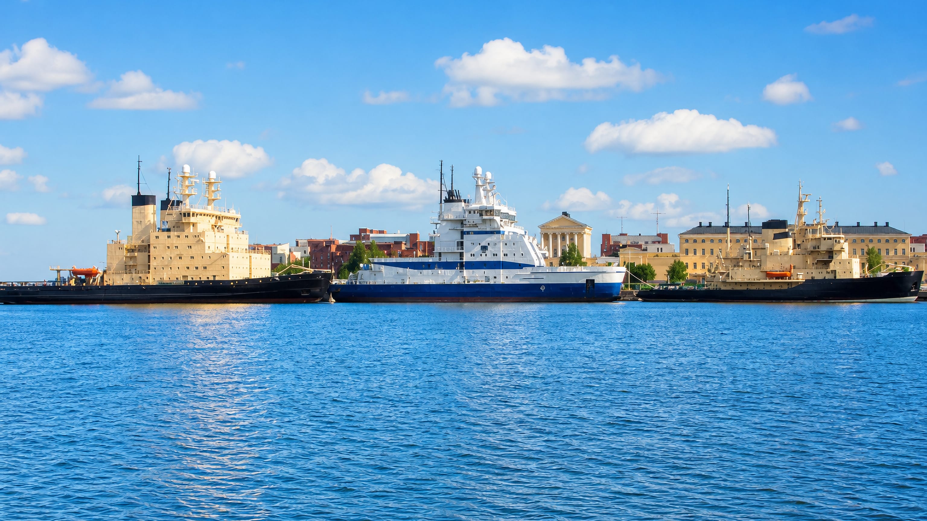 Icebreaker fleet moored along the Katajanokka quay in Helsinki with neoclassical waterfront buildings behind.